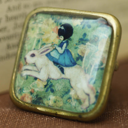 Alice riding the white rabbit in Wonderland square ring, Jewelry by Danita Art