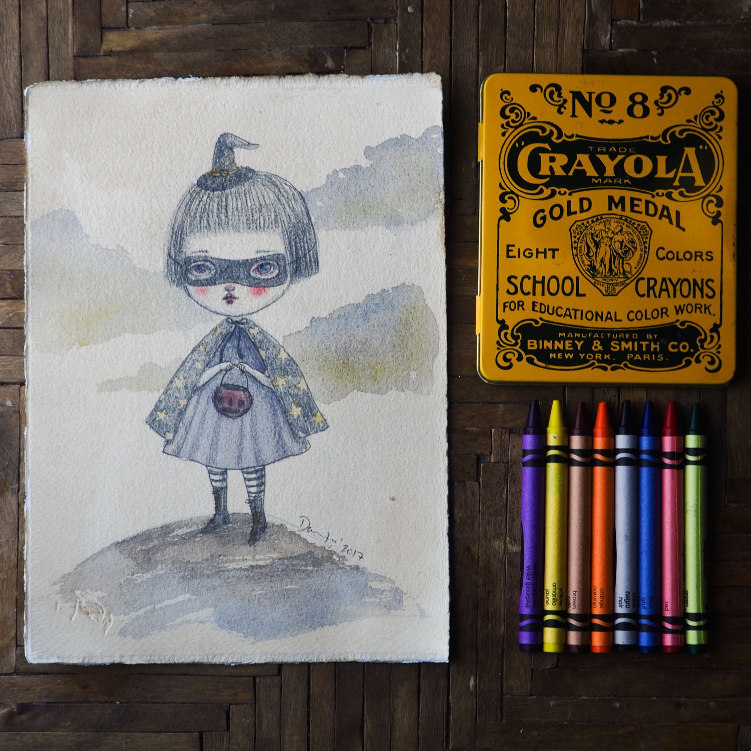 Danita original watercolor pencil painting. Whimsical witch trick-or-treat Halloween night. She has her cape, a mask and a little jack-o-lantern on her hands.