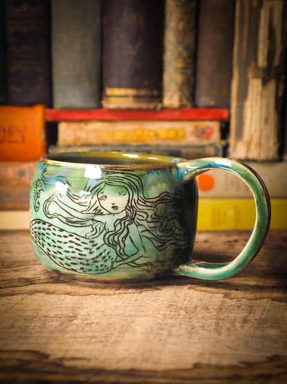 This is a handmade ceramic coffee or tea mug, create entirely by Idania Salcido, the artist behind Danita Art. The mermaid swimming on this mug is hand painted before glazing it and firing it on my very own kiln. It will be perfect for driving your favorite coffee or tea, in company of a beautiful mermaid.