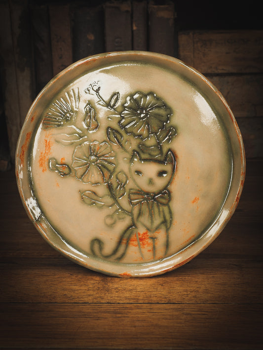 An original Idania Salcido Danita Art pinched ceramic cat pet food plate. Handmade from stoneware, this glazed ceramics one of a kind artwork is perfect for any kitchen plate and bowls unique collection. Thumbprints and  intentionally irregular shape give the bowl a cozy, warmly familiar feel when you pick it. A cute little cat hiding in flowers is carved on the sides.