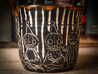 An original Halloween ceramic mug tumbler bowl handmade by Idania Salcido the artist behind Danita Art. Made with wheel thrown clay hand carved and glazed by the artist. Witches, ghosts, goblins and vampires give it a nice, folk art primitive feel to it. Perfect for Halloween Candy, ice cream and fruit, a pet cat bowl.