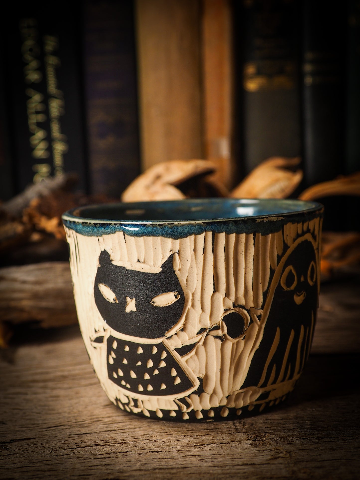 Fire glazed ceramic coffee mug by Idania Salcido, Danita Art. On Halloween, Danita creates ceramic containers for pumpkin spice coffee, warm tea or sweets to give on trick-or-treat night. With carved with Halloween ghosts, skeletons, witches, ghouls, black cats, jack-o-lanterns, item is food safe, hand wash only.