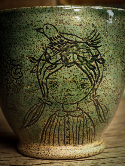 An original glazed ceramic mug by Idania Salcido, the artist behind Danita Art. It measures 4 x 4 x 3.5 Inches, with deep green hue glazes and hand decorated figures on the sides. Totally handmade in my studio, this is a unique piece that cannot be repeated. Food and drink safe, hand wash only.