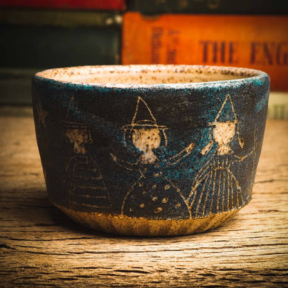 This little handmade ceramic halloween bowl by Idania Salcido Daita art has three witches carved on it, they are ready to cast a spell during a dark starry night, and you can see the magic stream from their wands in subtle bands of color across the deep, midnight blue sky. And of course, the moon and stars are there with them.