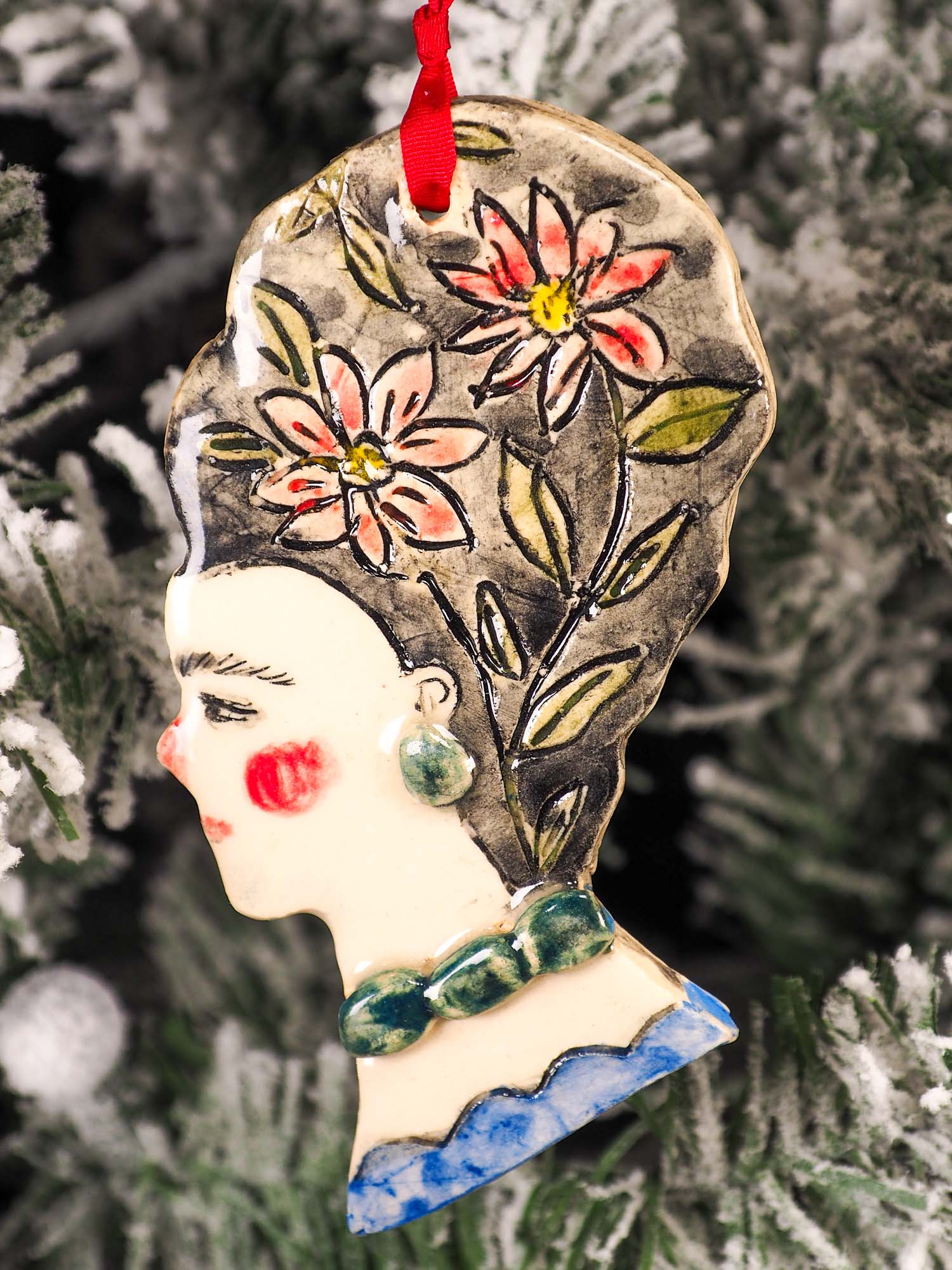 An original Christmas Holiday tree round glazed ceramic hanging ornament handmade by Idania Salcido, the artist behind Danita Art. Glazed carved sgraffito stoneware, hand painted and decorated, it is illustrated by hand with flowers, hearts, leaves, nature patterns and the face of Frida Kahlo.